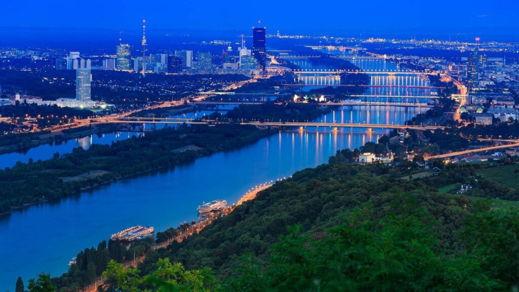 Night view of Vienna skyline with Danube river and illuminated bridges.